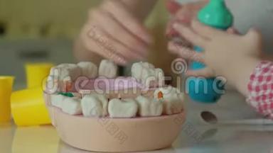 一个年轻的女人和一个女孩用塑料制成<strong>牙齿</strong>，把他们的<strong>牙齿</strong>插入玩具下巴，女孩钻他们的<strong>牙齿</strong>
